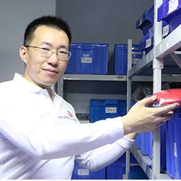 Zhang Wei, machining engineer, selecting a bearing component from stock